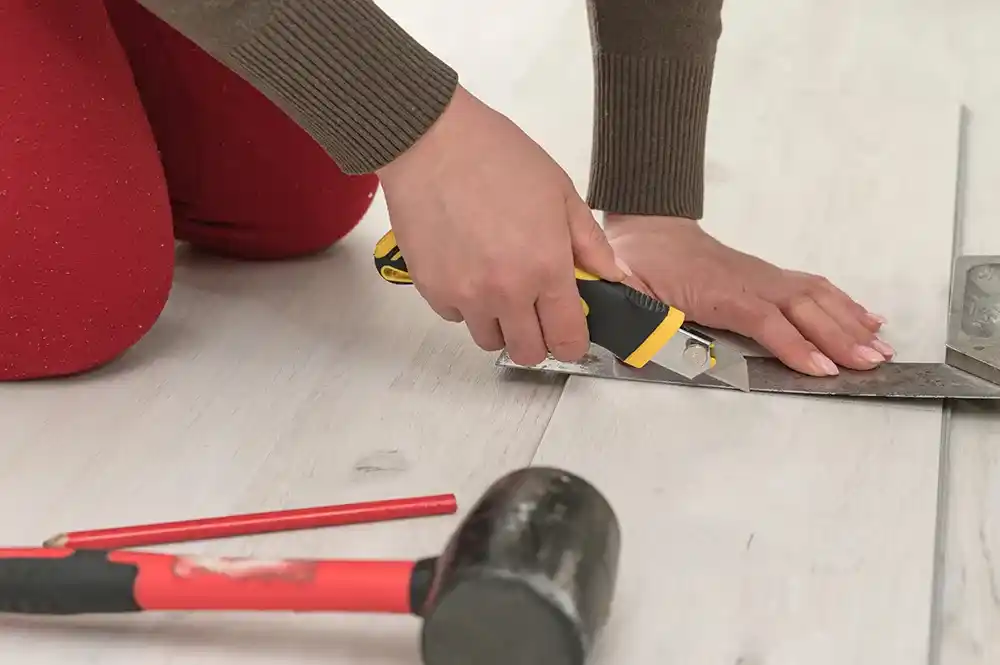 Close-up of a professional cutting flooring material with a utility knife for a precise installation